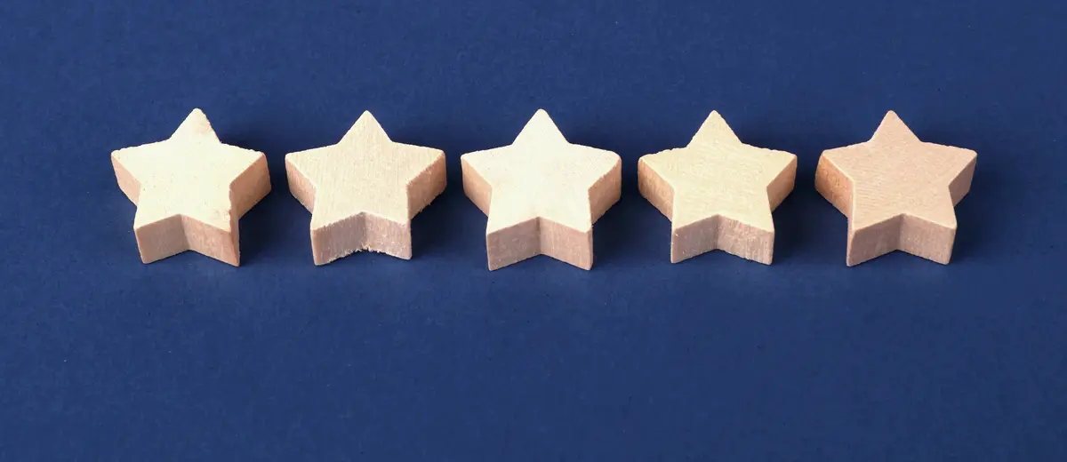 Five wooden stars in a row on a navy background.
